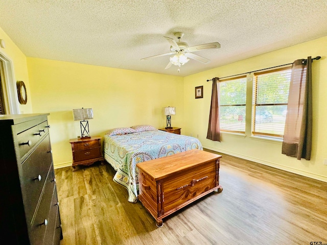 bedroom with ceiling fan, wood-type flooring, and a textured ceiling