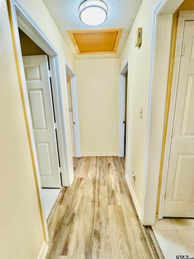 hall featuring a textured ceiling and light wood-type flooring