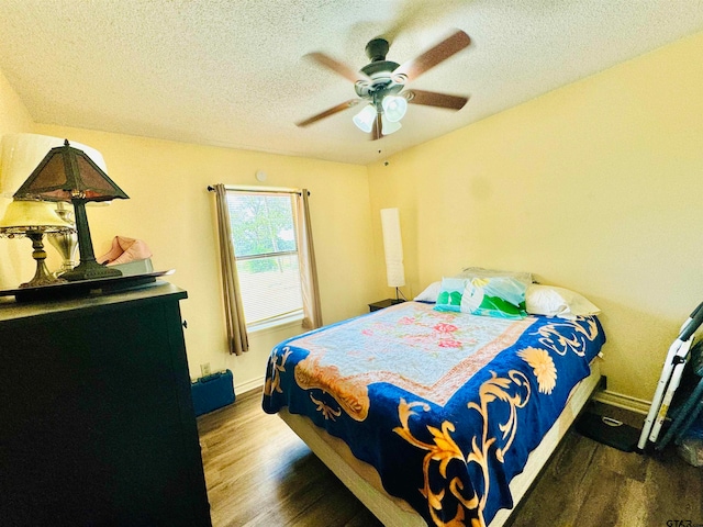 bedroom with ceiling fan, a textured ceiling, and dark hardwood / wood-style flooring