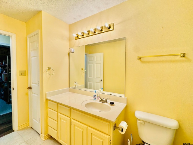 bathroom with toilet, vanity, a textured ceiling, and tile patterned flooring