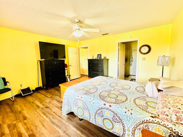 bedroom with hardwood / wood-style flooring, ceiling fan, and a textured ceiling