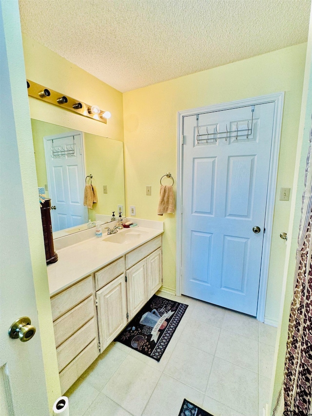 bathroom with vanity, a textured ceiling, and tile patterned flooring