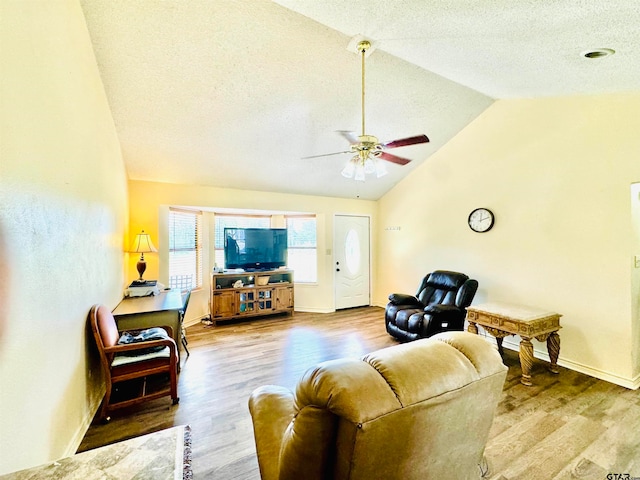 living room featuring hardwood / wood-style floors, vaulted ceiling, ceiling fan, and a textured ceiling