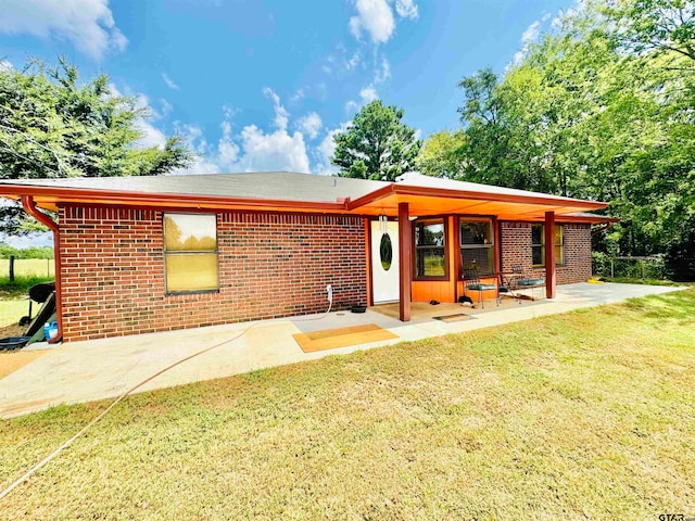 back of property featuring a lawn and a patio area