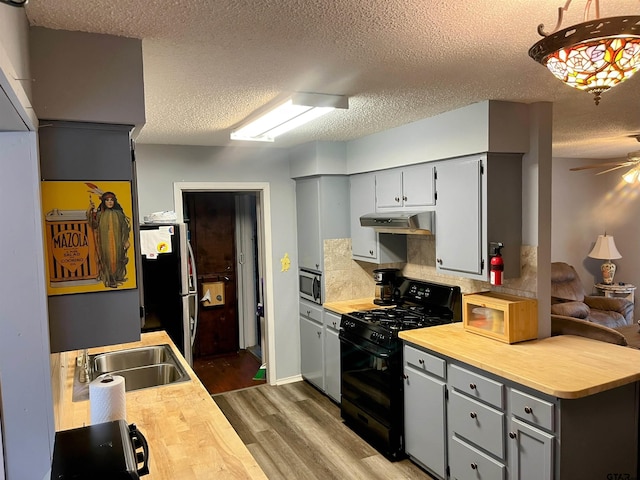 219 Lockhart St, Pittsburg, TX 75686 - kitchen featuring appliances with stainless steel finishes, under cabinet range hood, dark wood-style floors, gray cabinets, and a textured ceiling