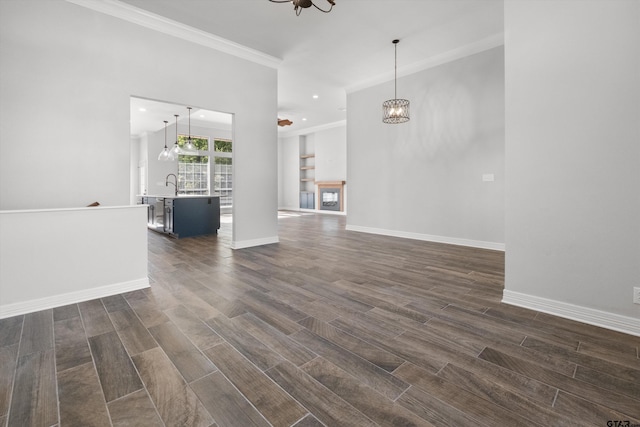 3827 Scenic Dr, Tyler, TX 75709 - unfurnished living room with a chandelier, ornamental molding, dark wood-style floors, baseboards, and a sink