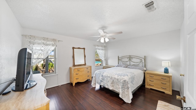 bedroom featuring multiple windows, ceiling fan, dark hardwood / wood-style floors, and a textured ceiling