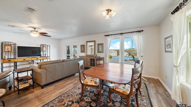 dining room featuring wood-type flooring, ceiling fan, a textured ceiling, and french doors