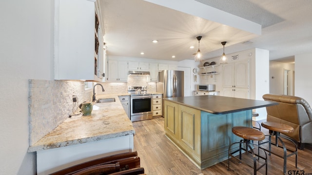 kitchen with sink, a kitchen island, pendant lighting, stainless steel appliances, and white cabinets