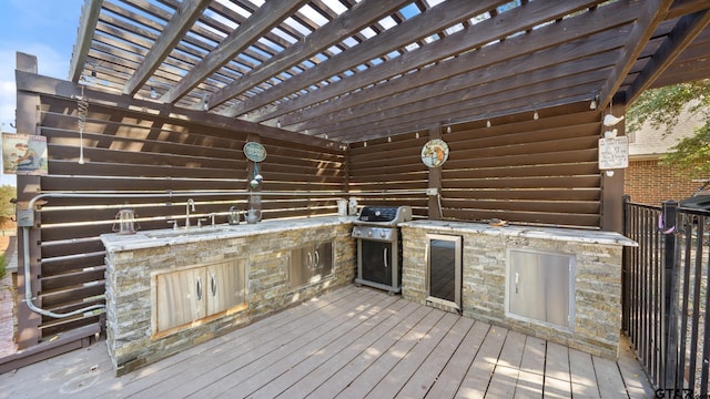 wooden terrace with sink, a pergola, grilling area, and an outdoor kitchen