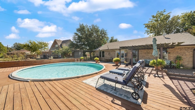 view of swimming pool with a wooden deck and a pergola