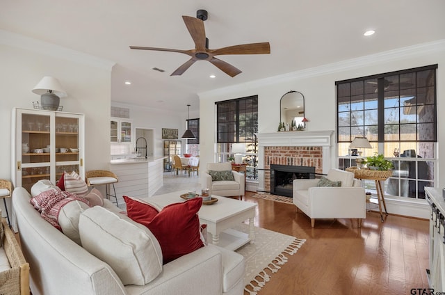 110 Carmel, Bullard, TX 75757 - living room featuring ornamental molding, a ceiling fan, wood finished floors, a brick fireplace, and recessed lighting