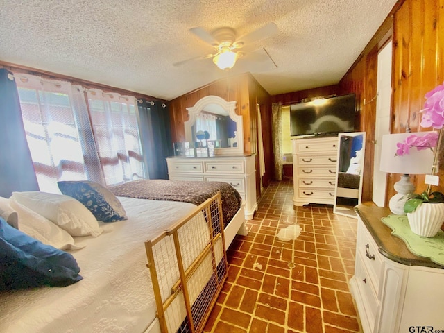 710 N 6th St, Crockett, TX 75835 - bedroom with a ceiling fan, a textured ceiling, wood walls, and brick floor