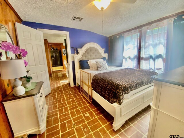 710 N 6th St, Crockett, TX 75835 - bedroom featuring visible vents, a ceiling fan, a textured ceiling, and brick floor