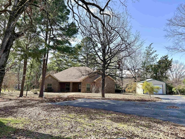 view of front of house featuring a garage, brick siding, and an outdoor structure