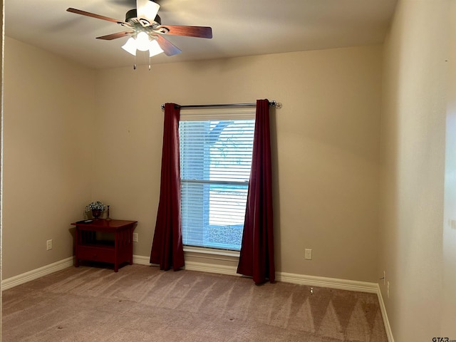 spare room with light carpet, ceiling fan, and baseboards