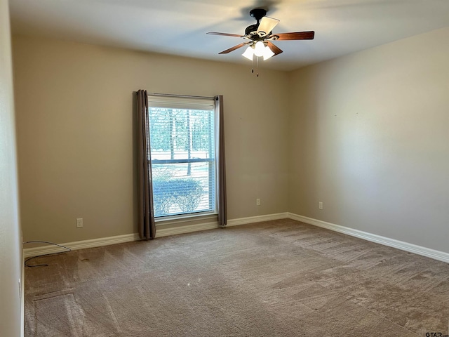 carpeted empty room with ceiling fan and baseboards