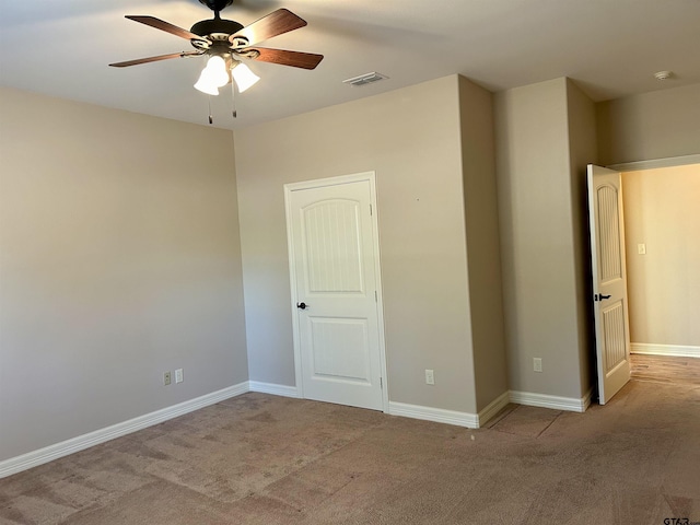 carpeted empty room featuring visible vents, ceiling fan, and baseboards