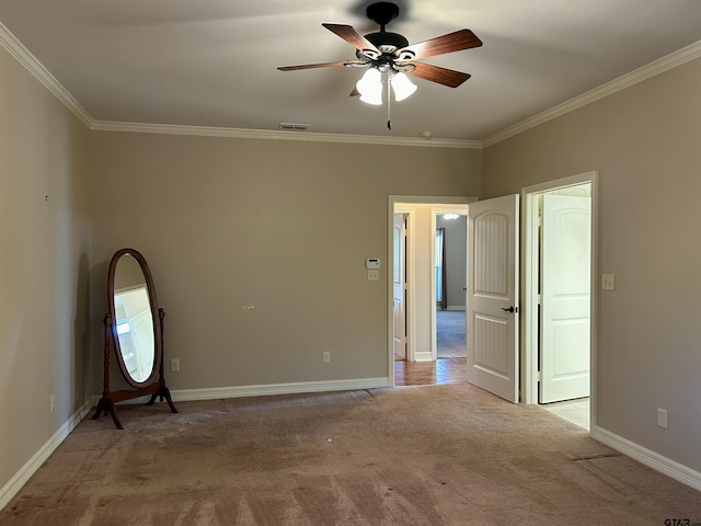 spare room featuring ornamental molding, light carpet, ceiling fan, and baseboards