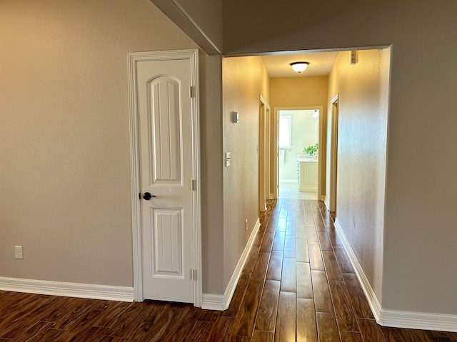 corridor with dark wood-style floors and baseboards