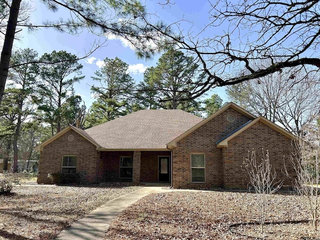 ranch-style house featuring brick siding and roof with shingles