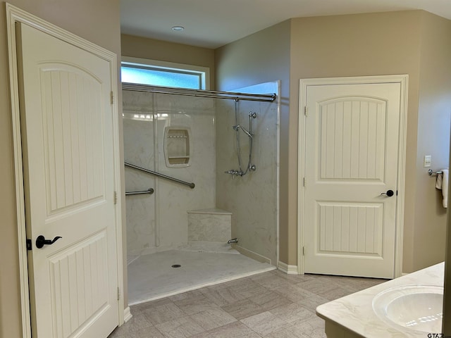 bathroom featuring a marble finish shower and vanity