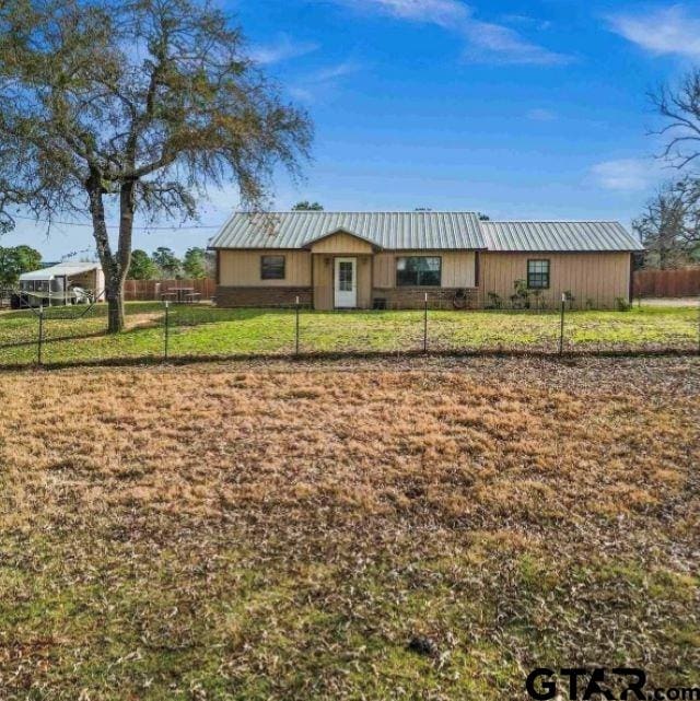 single story home featuring metal roof, a front lawn, and fence