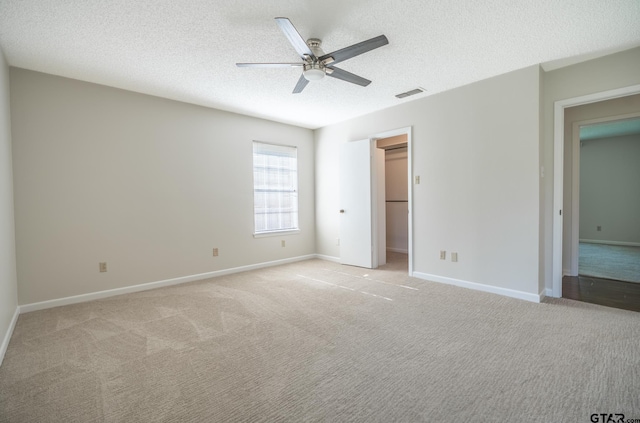902 Joel Dr, Tyler, TX 75703 - unfurnished bedroom featuring light colored carpet, a textured ceiling, baseboards, ceiling fan, and a walk in closet