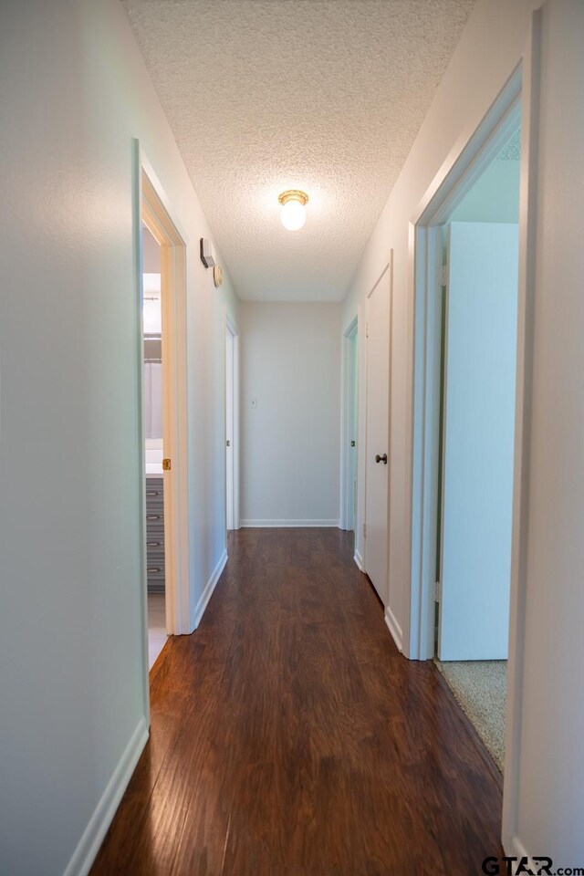 902 Joel Dr, Tyler, TX 75703 - hallway with wood finished floors, a textured ceiling, and baseboards