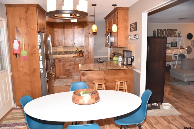 607 Brookhollow Dr, Palestine, TX 75801 - kitchen featuring stainless steel appliances, tasteful backsplash, brown cabinets, light wood-type flooring, and a peninsula