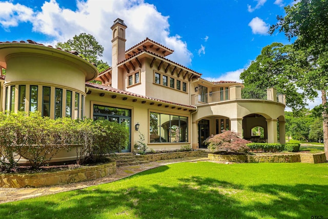 rear view of house featuring a lawn and a balcony