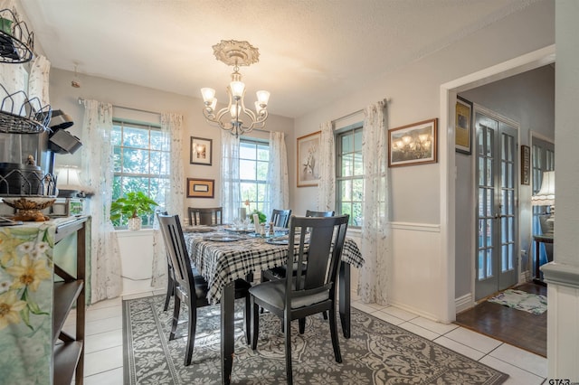 dining area featuring a notable chandelier, light tile patterned floors, and a textured ceiling