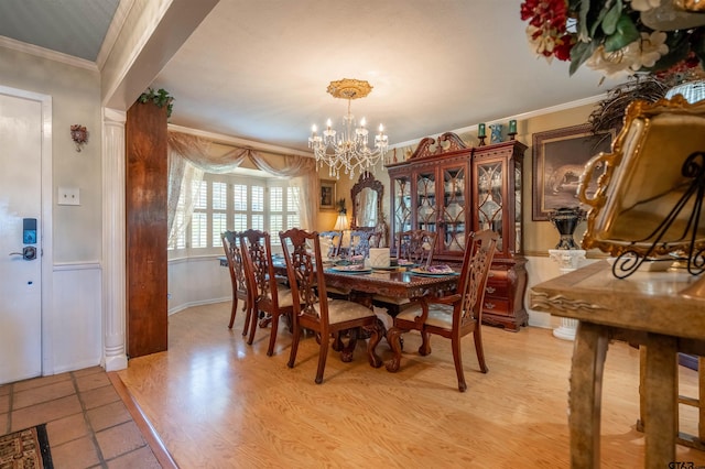 dining area featuring ornamental molding, a notable chandelier, and light wood-type flooring