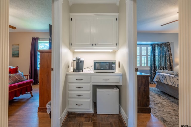 kitchen featuring ceiling fan, white cabinetry, a textured ceiling, and dark hardwood / wood-style flooring