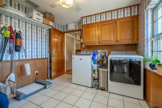 clothes washing area with a textured ceiling, washer and clothes dryer, cabinets, a healthy amount of sunlight, and light tile patterned flooring