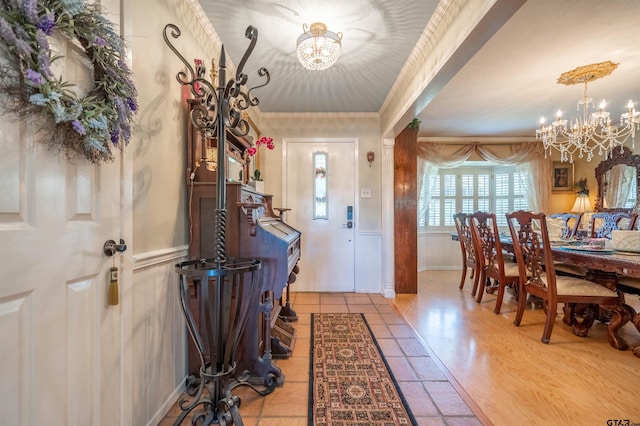 tiled foyer with crown molding and a notable chandelier