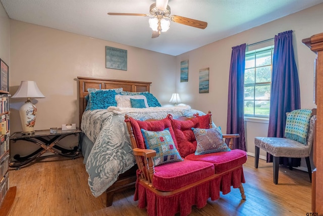 bedroom featuring ceiling fan, hardwood / wood-style floors, and multiple windows