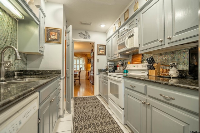 kitchen with sink, light tile patterned flooring, white appliances, and tasteful backsplash