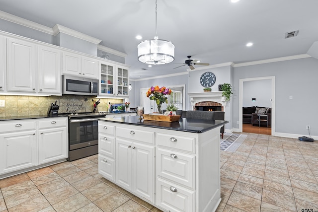 5201 Whitaker Cir, Longview, TX 75605 - kitchen featuring appliances with stainless steel finishes, dark countertops, a brick fireplace, ornamental molding, and ceiling fan