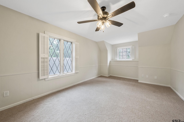 carpeted empty room featuring a wainscoted wall and ceiling fan