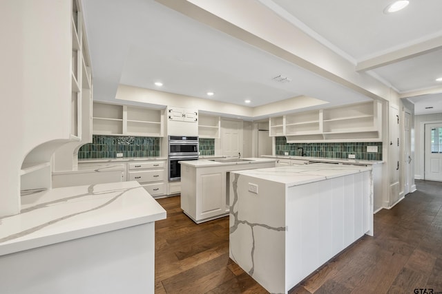 kitchen featuring double oven, open shelves, dark wood-type flooring, and a center island