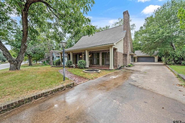 view of front of house with a garage, driveway, a chimney, and a front lawn