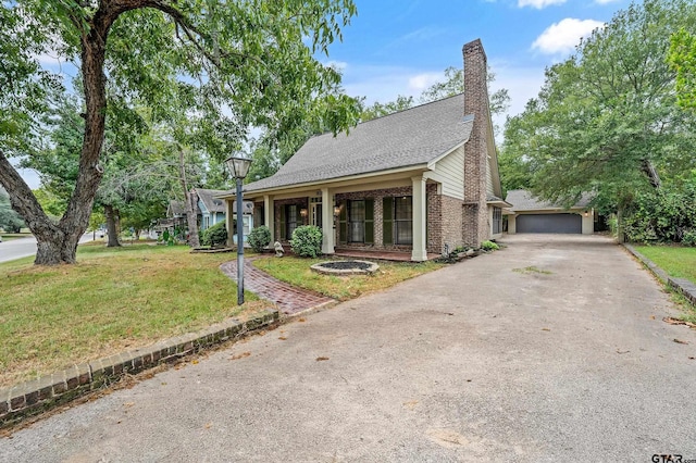 view of front of property with driveway, a chimney, and a front yard