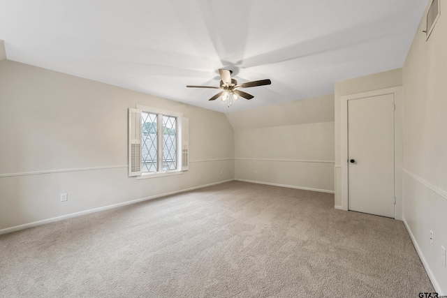 carpeted empty room with visible vents, baseboards, lofted ceiling, and a ceiling fan