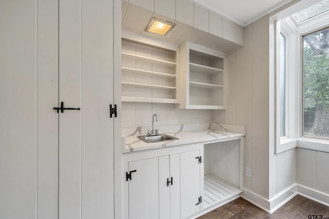 bar with wet bar, baseboards, and a sink