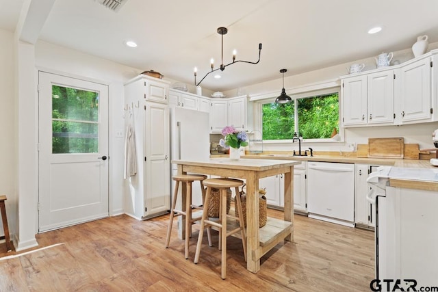 kitchen with light hardwood / wood-style floors, white cabinets, a notable chandelier, pendant lighting, and white appliances