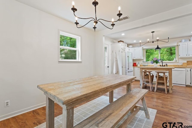 dining area featuring a wealth of natural light, a notable chandelier, sink, and light hardwood / wood-style flooring