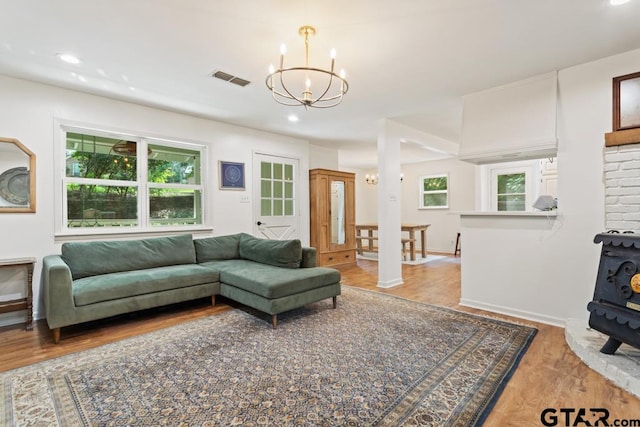 living room featuring a wood stove, light wood-type flooring, and an inviting chandelier