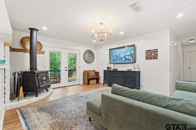 living room featuring an inviting chandelier, a wood stove, and light hardwood / wood-style floors