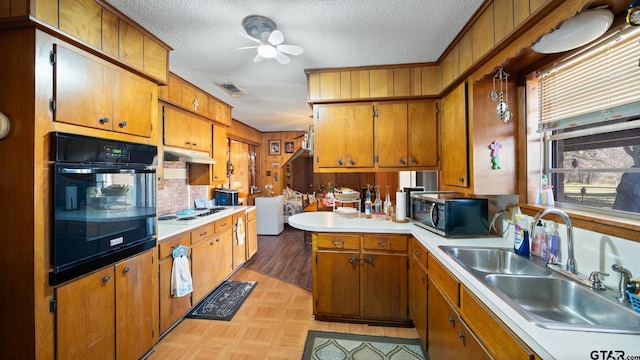 kitchen with ceiling fan, sink, white gas stovetop, oven, and a textured ceiling